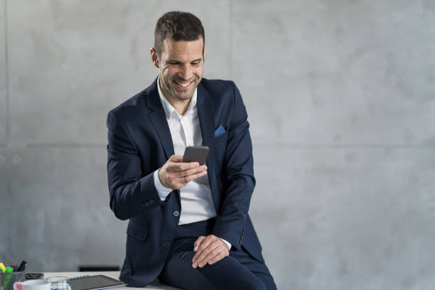 istock Smiling male entrepreneur using smart phone in the office. 1471363279