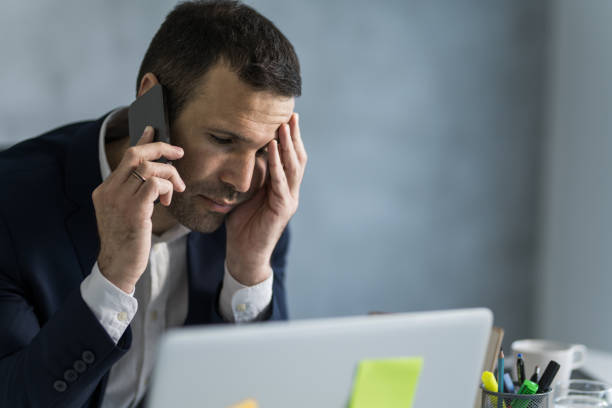 istock Worried businessman talking on mobile phone while working on laptop in the office. 1471363627