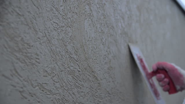 Worker applies textures stucco with putty on wall in room
