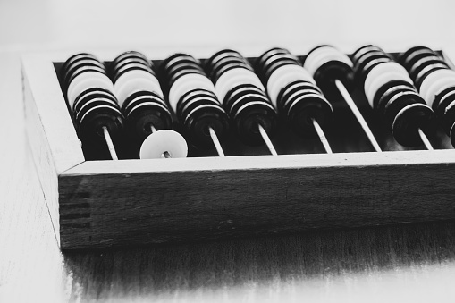 Old wooden abacus for counting money on a wooden table close-up black and white photo