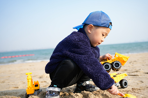 The little boy is playing with his toys on the beach