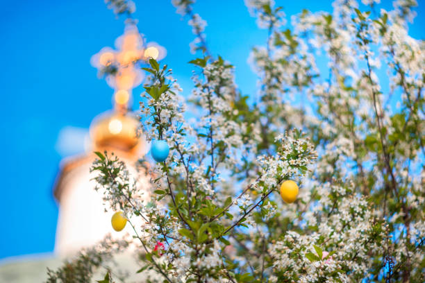 Easter eggs on flowering branches of a tree against the backdrop of the temple. Easter