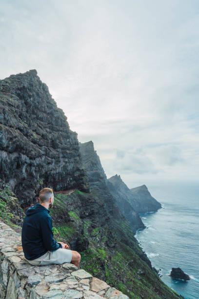 istock Man sitting at a viewpoint looking the seascape in a cloudy day 1471373232