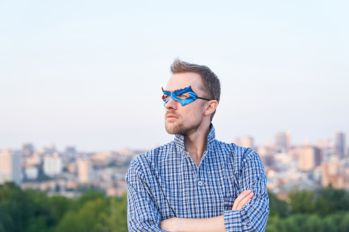 Caucasian male in sleep wear shirt and superhero blue mask looking at side with serious face. Superpower or positive expression concept. High quality image