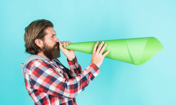 istock False advertising concept. Handsome man shouting through speaker. loud announcement. dont be silent. vote. urge the public. Do not be afraid to express your opinion. free man shouting into megaphone 1471377295