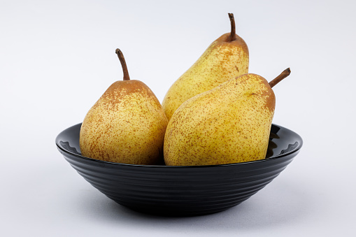 Three pears on a black plate.