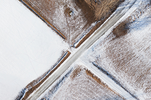 A country road with various snow covered fields around it.
