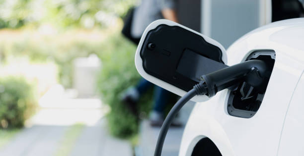 istock Focus EV charging station at home with blur progressive man in background. 1471384107