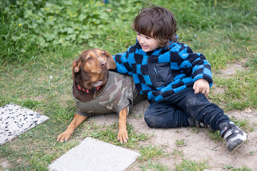 Little boy is sitting on the ground with the dog