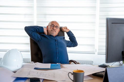 Senior architect man suffering from neck pain in office