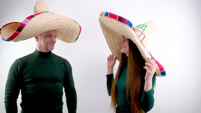 man and woman on white background in Mexican sombrero hats huge hat dressed he points finger as if is offering trip waiting for warmth of sea for relaxation Travelers fun travel agency ticket to sea