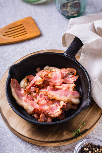 istock Crispy strips of bacon fried in a pan on the table. Vertical view 1471391833