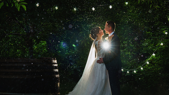 a bride and groom is dancing happily in the rain