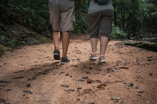 Low section of an unrecognizable senior couple hiking through the tropical forest.