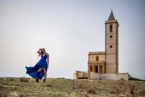 Photo of Serene Beauty: A Blue-Dressed Woman and a Church on a Blue Day