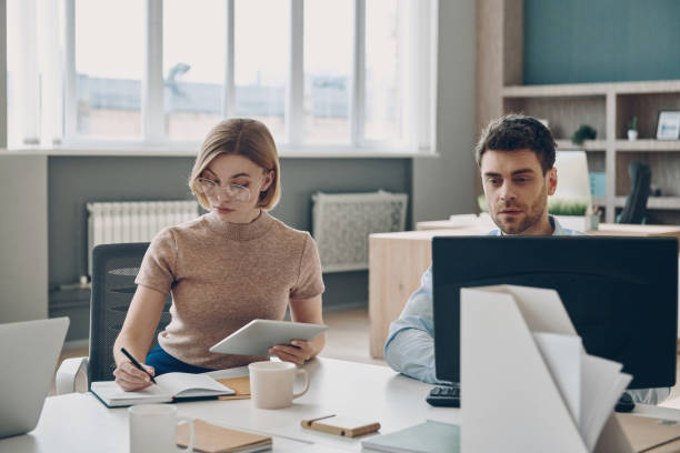 istock Two confident business people working together while sitting at the desk in office 1471404599