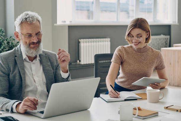 istock Two confident business people working together and smiling while sitting at the office desk 1471404610