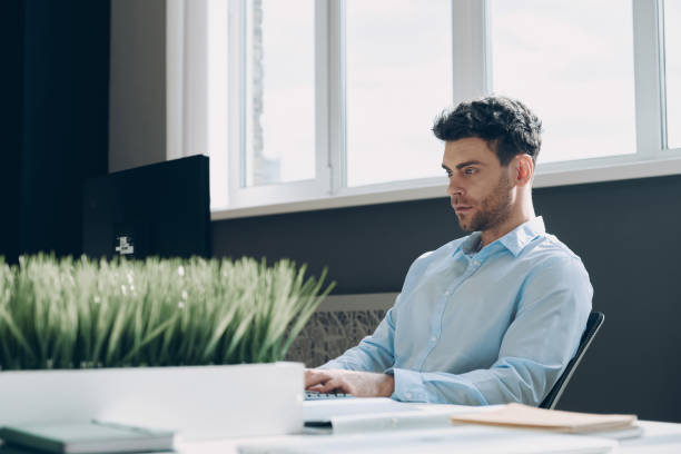 istock Confident young businessman using computer while sitting at his working place in office 1471405630
