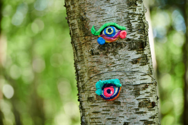 Art object of human eyes on tree trunk in green forest background, trees sight feeling ecological concept