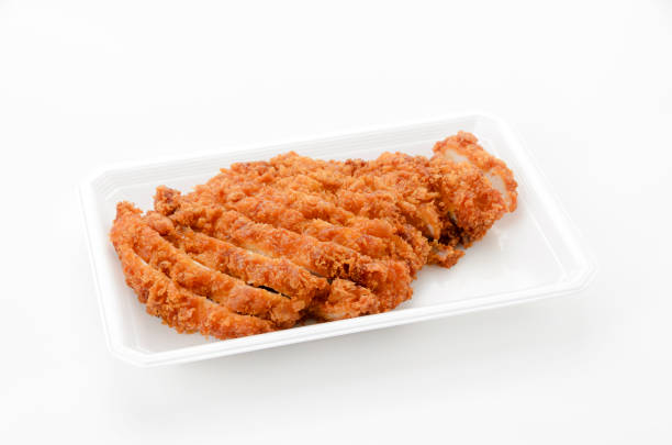 Sliced chicken cutlet on a food tray on white background