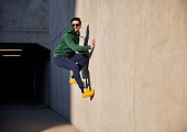 Young adult man wearing sports wear jumping on concrete wall during sunny afternoon in the city