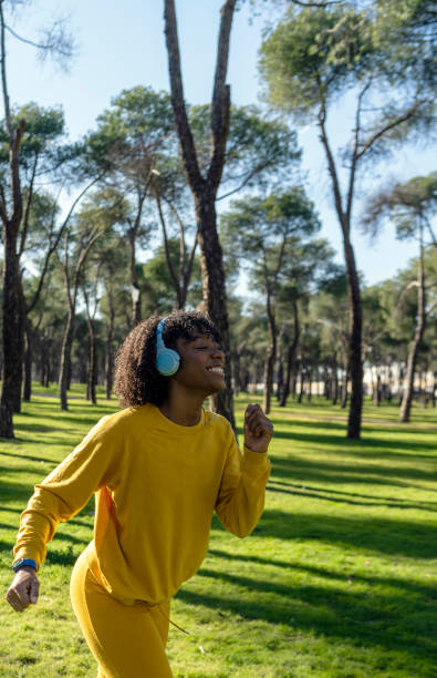 A girl in a yellow tracksuit jogs in the park stock photo