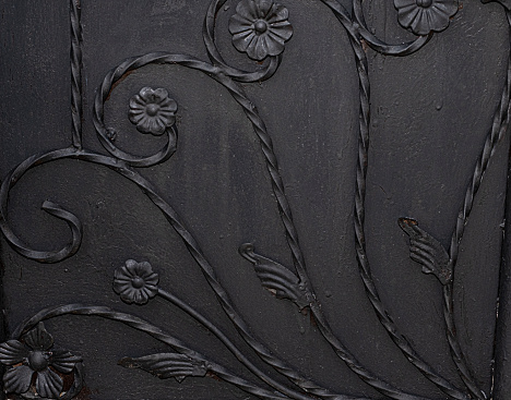 Close up of black metal gate panel with twisted rods as stems with flowers design