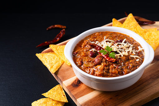 Food concept Homemade Chili con carne on wooden board and black slate stone background with copy space
