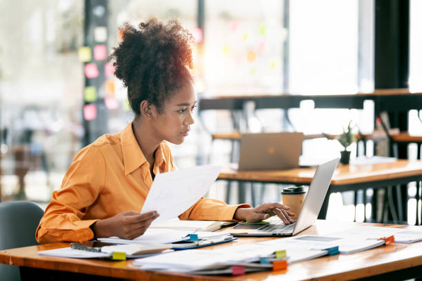 istock Young ethnic businesswoman looking seriously working on laptop computer and document at her desk office. 1471417616