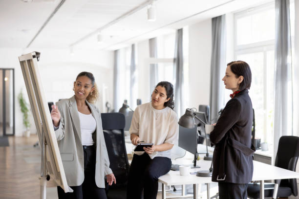 istock Woman executive pointing at whiteboard and discussing with team at startup 1471419631