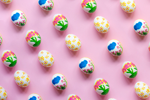 Painted easter eggs in a row on pink background