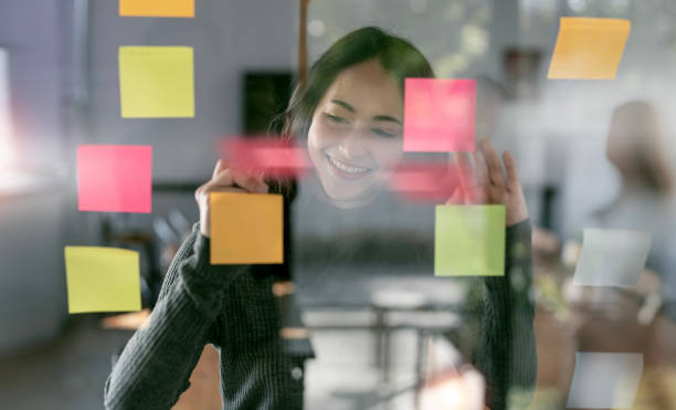 istock Creative businesswoman writing on sticky notes on a glass wall 1471419812
