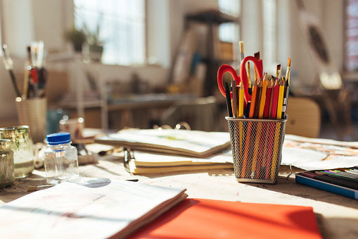 Desk of an artist with brushes, wooden crayons, and canvases