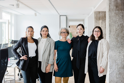 Portrait of group of female colleagues at work. Multiracial woman professionals standing together in office looking at camera.