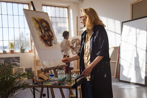 At the studio, two female artists are painting on canvas