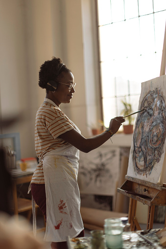 A lovely young woman artist spends the day painting and listening to music in her studio