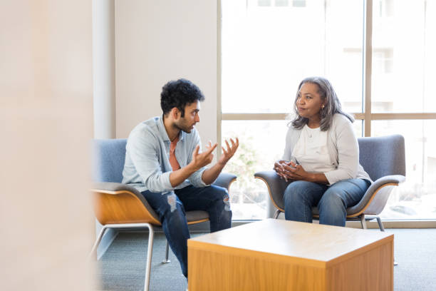 istock Young man gestures while sharing with female counselor 1471421359