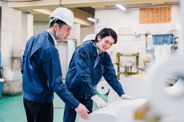 Workers checking paper rolls at a printing plant