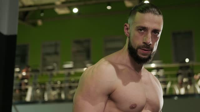A handsome muscular man with a beard poses in the gym. Sports and healthy lifestyle