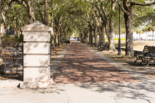 Pillar and tree-lined, shaded brick walkway in Charleston Riverfront Park stock photo