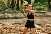 Female portrait of woman who playing beach volleyball outdoors. Lifestyle sports photography with people. Person wear black sports clothing with ball.