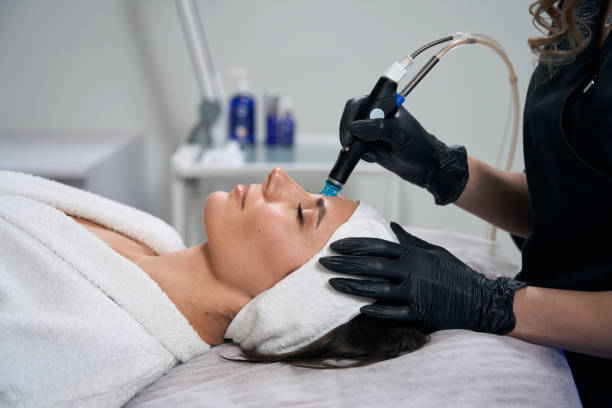 beautician doing facial skin rejuvenation for pretty female - alternative therapy massaging clinic health spa imagens e fotografias de stock