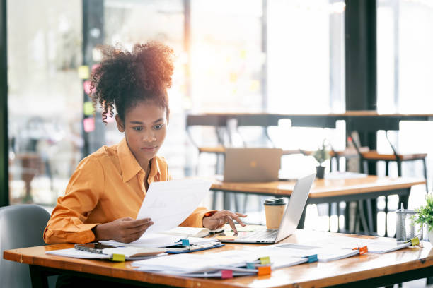 istock Young ethnic businesswoman looking seriously working on laptop computer and document at her desk office. 1471428884