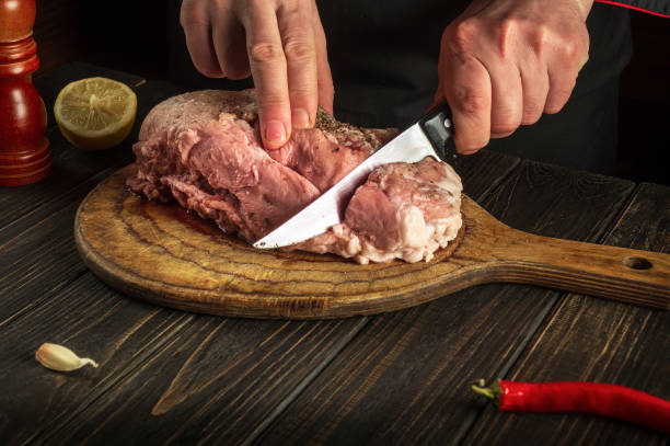 istock Chef cuts meat with a knife before baking. Spices on the kitchen table in a restaurant for preparing a delicious lunch or dinner 1471429714