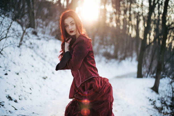 Beautiful winter portrait of young bond woman at Christmas tree and snow outdoors. Pretty long hair girl at New Year decoration wears national costume.