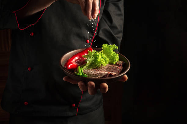 istock A professional chef sprinkles salt on a sliced beef steak and vegetables in a plate. The concept of serving dishes to order 1471432196