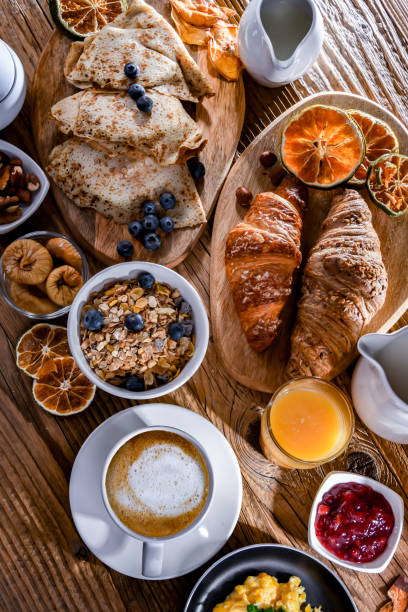 desayuno servido con café, huevos, cereales y croissants - breakfast fotografías e imágenes de stock