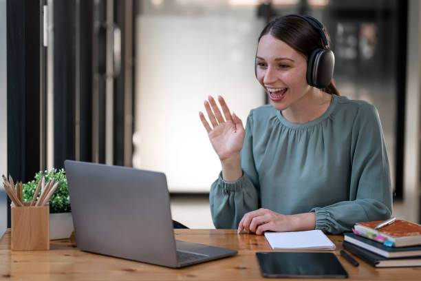 istock Young woman with headphone doing video call via laptop computer while sitting office. 1471435074