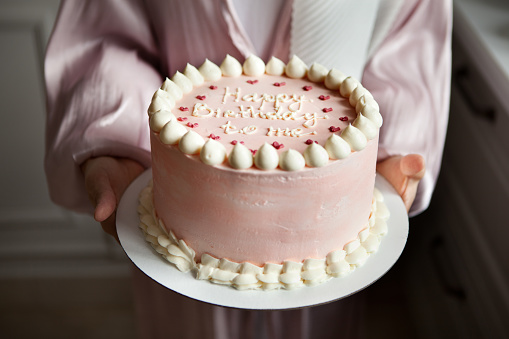 Woman holding delicious pink cake with text Happy birthday to me, closeup