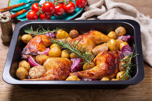 Chicken legs with potatoes and rosemary in a baking dish stock photo